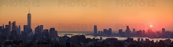 Waterfront cityscape under golden sky at sunset. New York City, New York, USA.