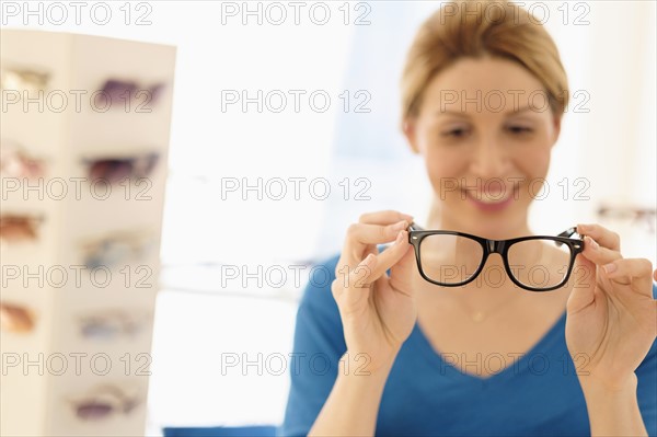 Woman and choosing eyeglasses in store.