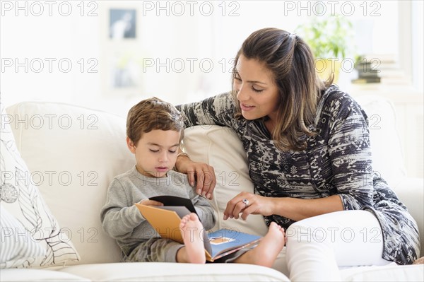 Mother reading with son (2-3) on sofa.