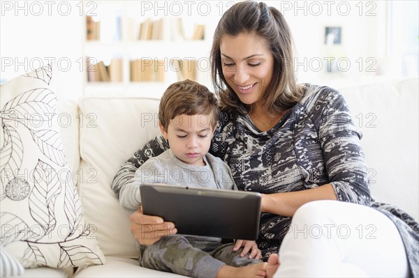 Mother reading with son (2-3) on sofa.