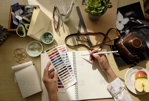 Overhead view of female hands writing in note pad.