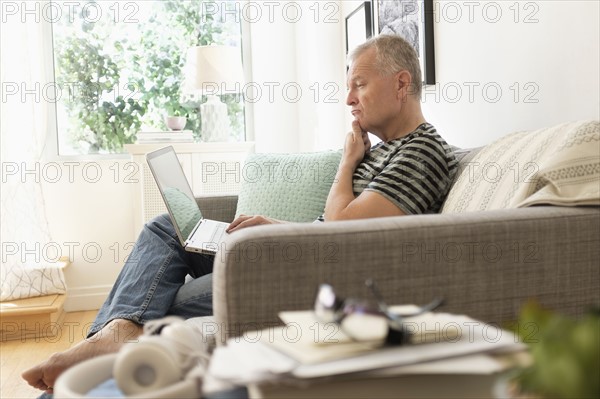 Man sitting on sofa using laptop.