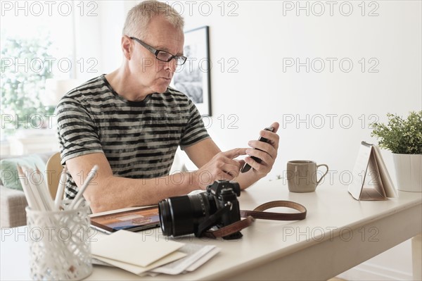 Man in home office using smartphone.