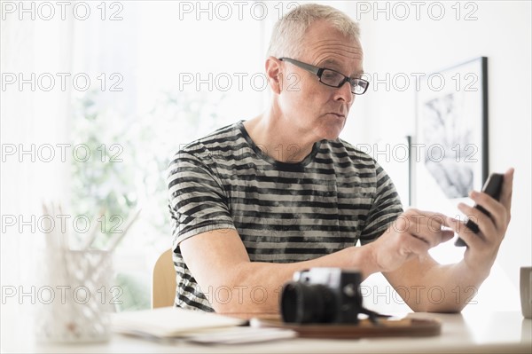 Man in home office using smartphone.