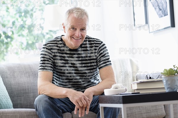 Portrait of smiling man sitting on sofa at home.