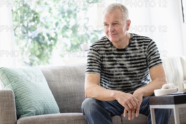 Portrait of man sitting on sofa at home.