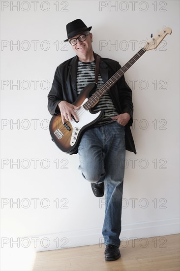 Man playing bass guitar in empty room.