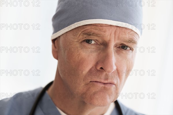 Portrait of surgeon in scrubs and surgical cap.