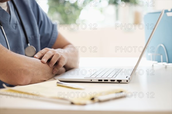 Man in scrubs using laptop.