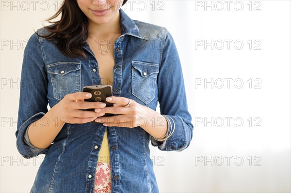 Mid-section of young woman texting.