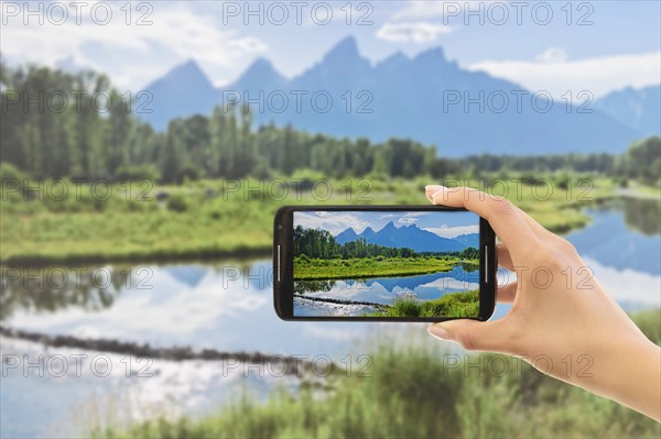 Hand photographing lake. Grand Tetons, Grand Teton National Park, Wyoming, USA.