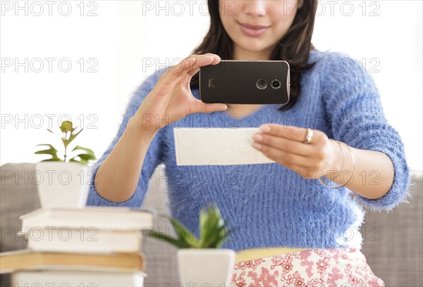 Young woman photographing bank statement.