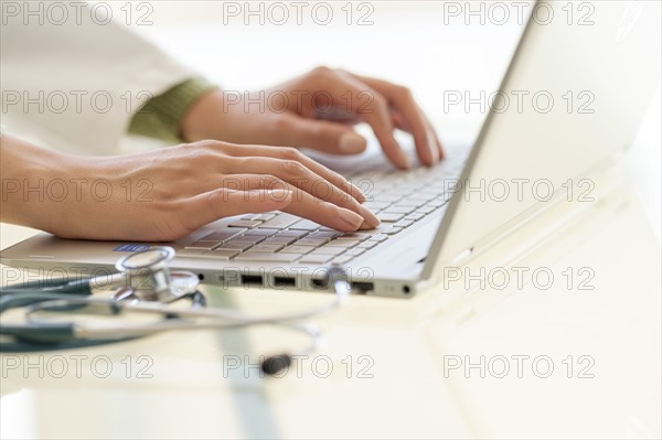 Hands typing on laptop keyboard.