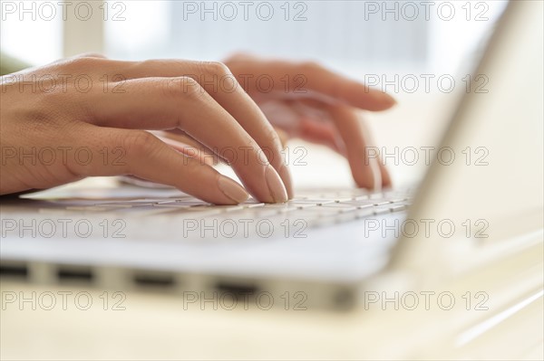 Hands typing on laptop keyboard.