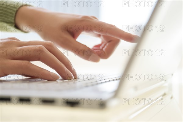 Hand typing at laptop.