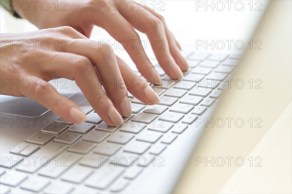 Hands typing on laptop keyboard.