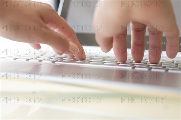 Hands typing on laptop keyboard.