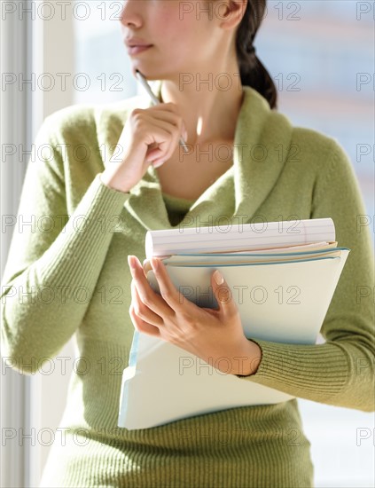 Mid section of business woman holding documents.