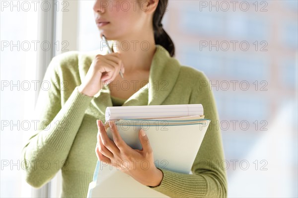 Mid section of business woman holding documents.