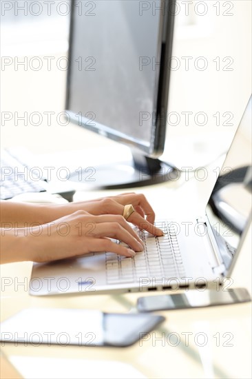 Hands typing on laptop keyboard.