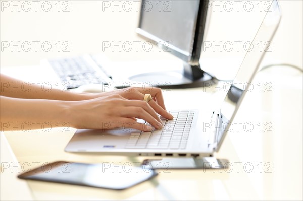 Hands typing on laptop keyboard.