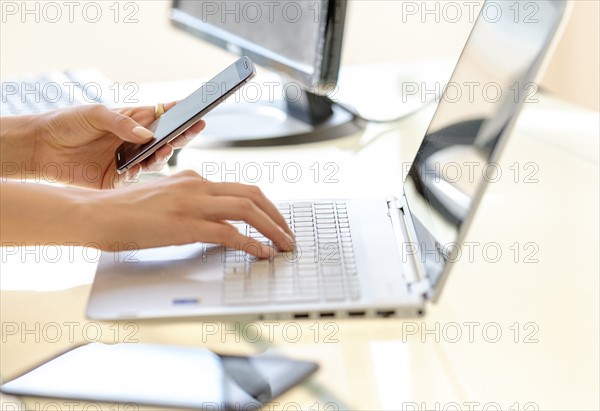 Business woman texting and typing on laptop keyboard.