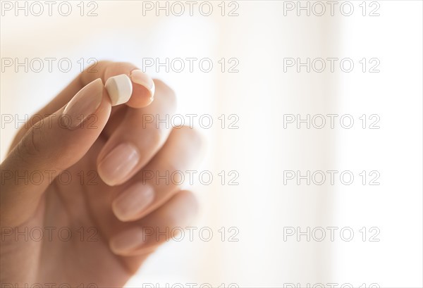 Hand holding vitamin pill.