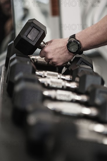 Man picking up dumbbells in health club.