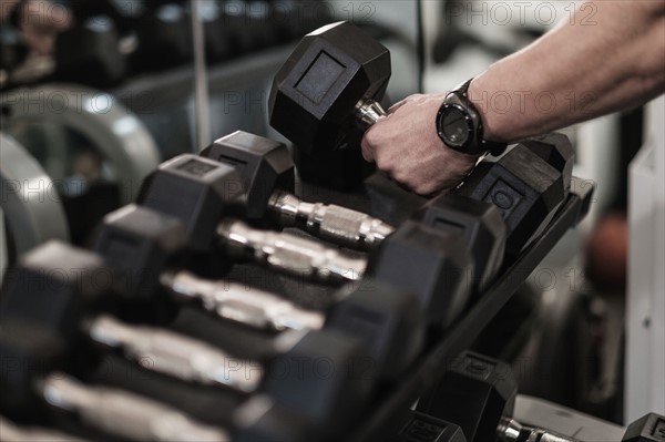 Man picking up dumbbells in health club.