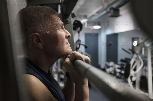 Man in health club doing chin-ups.