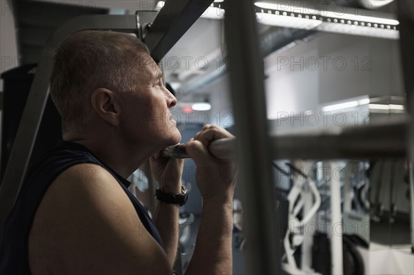 Man in health club doing chin-ups.