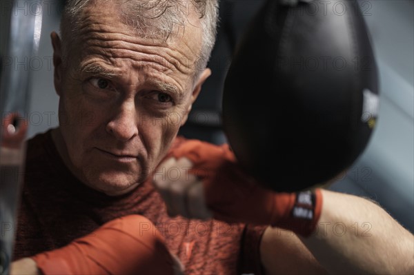 Man in health club hitting speed bag.