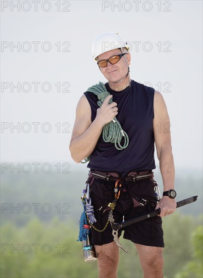 Portrait of man with climbing equipment outdoors.