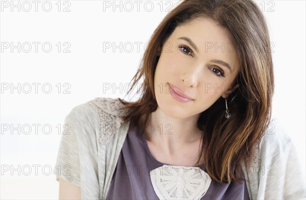 Studio shot portrait of smiling woman with brown hair.