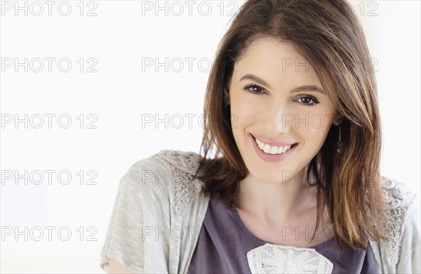 Studio shot portrait of smiling woman with brown hair.