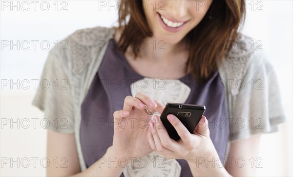 Smiling woman text messaging using smartphone.