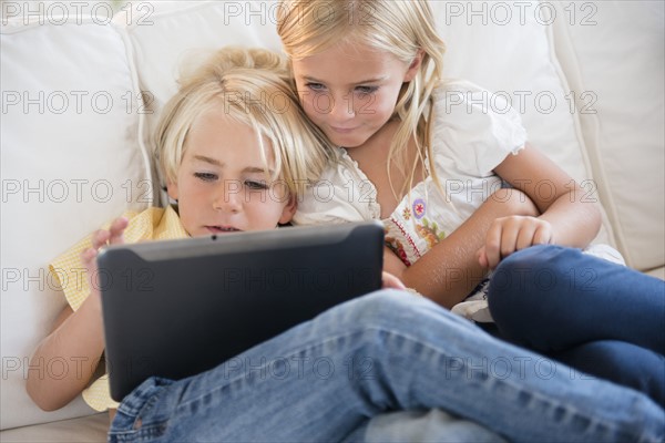 Girl (6-7) and boy (4-5) looking at digital tablet