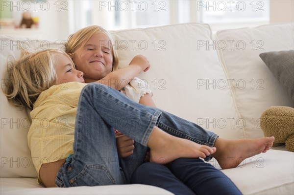 Boy (4-5) and girl (6-7) hugging on sofa