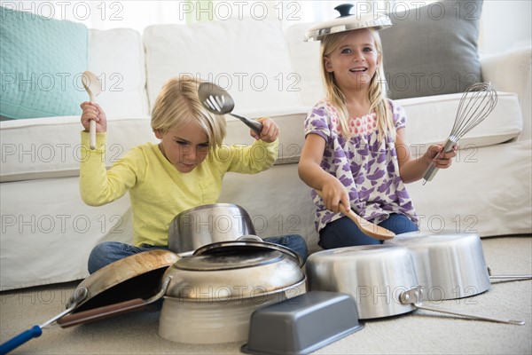 Boy (4-5) and girl (6-7) playing on pots on living room