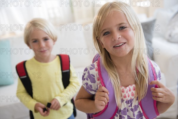 Boy (4-5) and girl (6-7) with backpacks, looking at camera