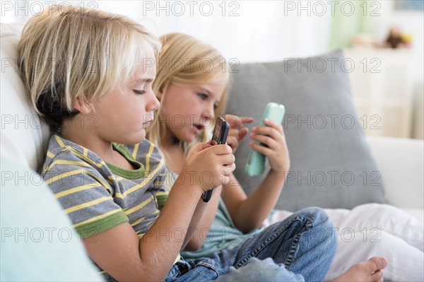 Boy (4-5) and girl (6-7) playing games on smart phones