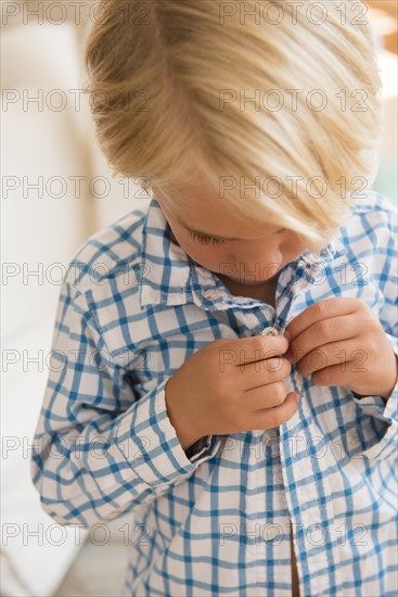 Boy (4-5) buttoning shirt