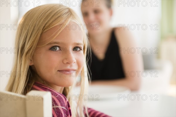 Girl (6-7) looking at camera and woman in background