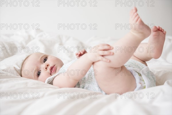 Baby girl (12-17 months) lying down on bed