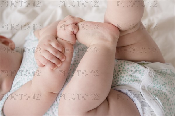 Baby girl (12-17 months) lying down with hands on feet