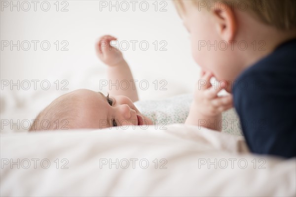 Baby girl (12-17 months) touching brother face (2-3)