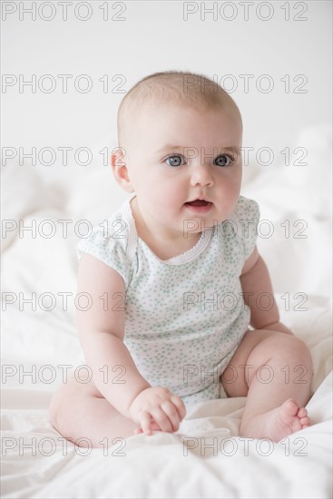 Baby girl (12-17 months) sitting on bed
