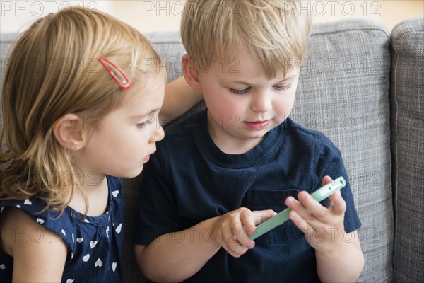 Brother with sister (2-3) playing with smart phone