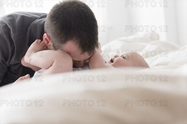 Father kissing baby daughter (12-13 months) belly