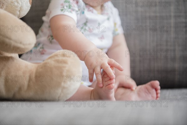 Baby girl (12-17 months) holding foot